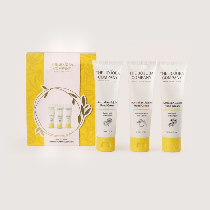 The Jojoba Company Australian Jojoba Hand Cream gift set, featuring a yellow and white box alongside three individual hand cream tubes with yellow caps, arranged on a light beige background.