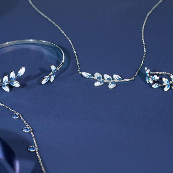Silver jewelry set with leaf designs on a blue background
