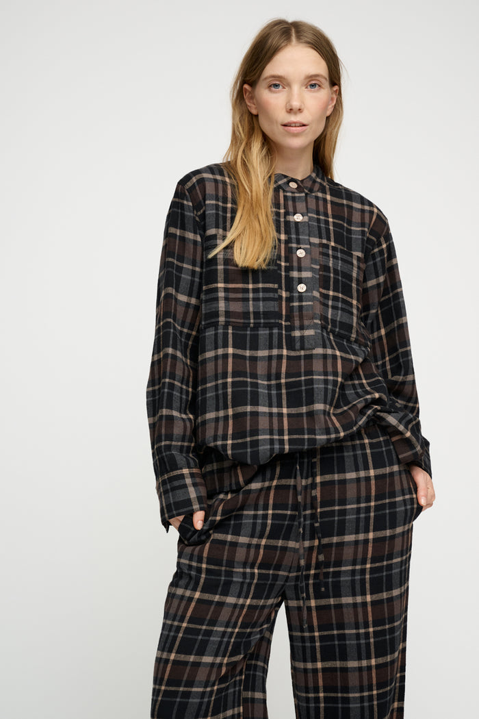 Person wearing a plaid shirt and pants on a white background