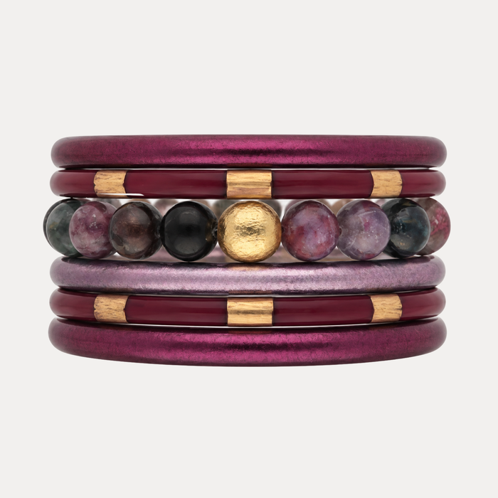 a stack of purple and gold bracelets